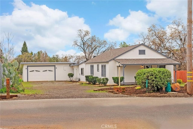 view of front of home featuring driveway, an attached garage, fence, and stucco siding