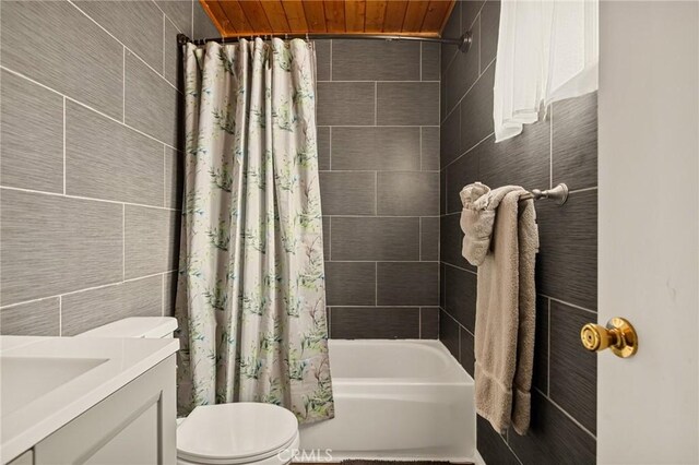 full bathroom featuring toilet, shower / bath combo with shower curtain, tile walls, and vanity