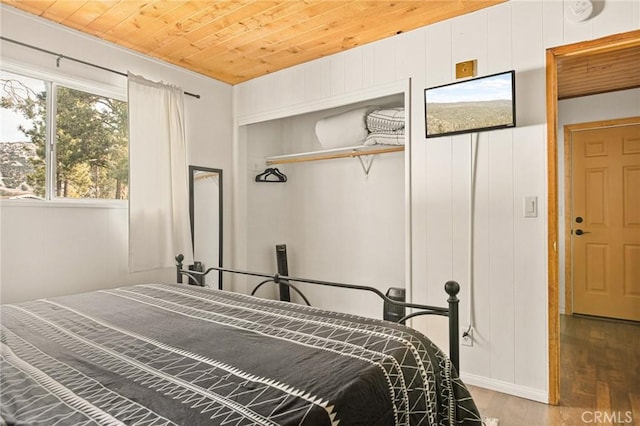 bedroom with a closet, wood finished floors, and wood ceiling