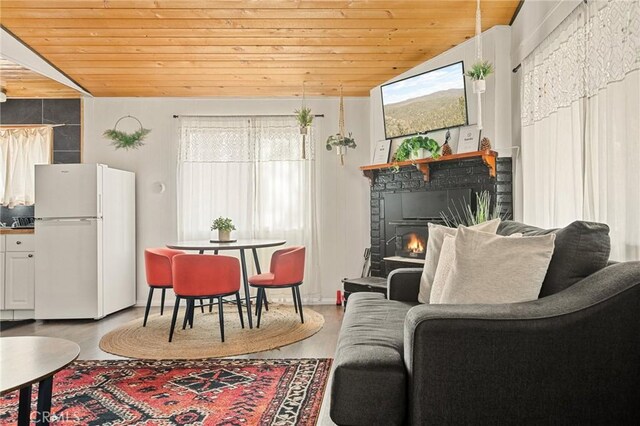 living room with lofted ceiling, a lit fireplace, wooden ceiling, and wood finished floors