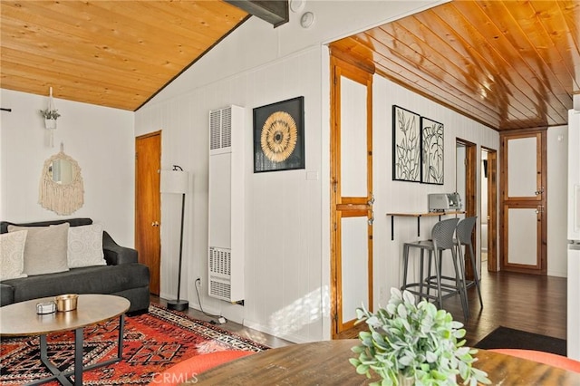 living area with lofted ceiling with beams, a heating unit, wood finished floors, and wood ceiling