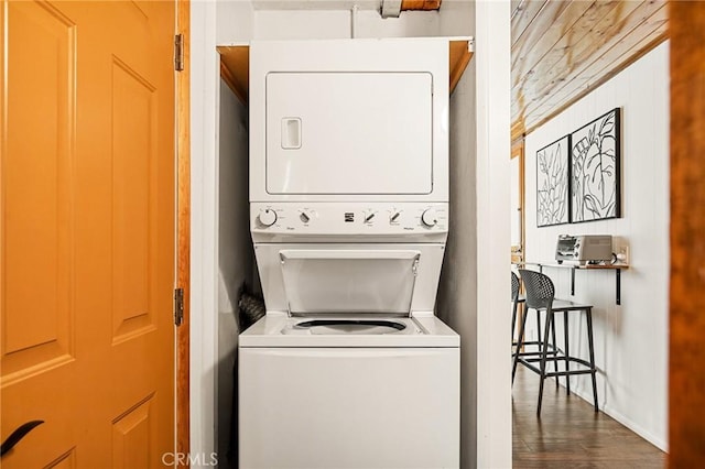 laundry room featuring laundry area, dark wood-style flooring, and stacked washer / drying machine