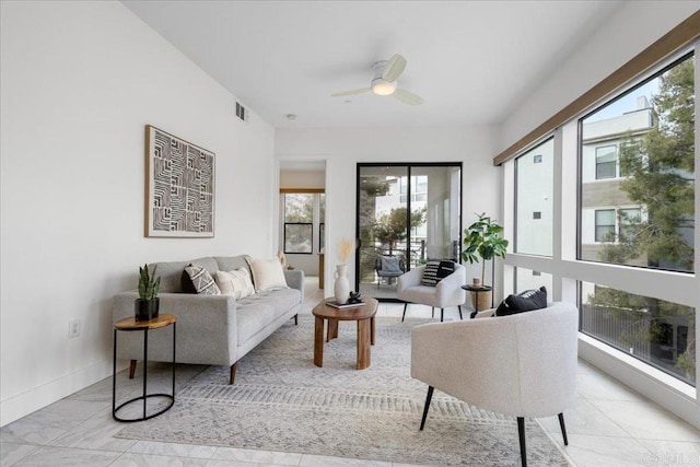 living area featuring a healthy amount of sunlight, a ceiling fan, visible vents, and baseboards