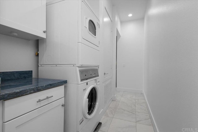 laundry area featuring recessed lighting, stacked washer / dryer, marble finish floor, and baseboards