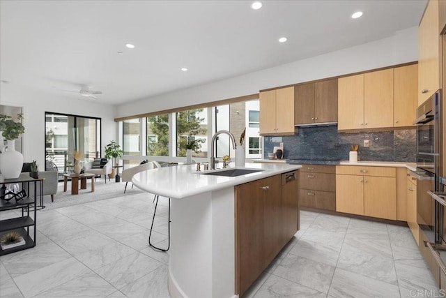 kitchen with decorative backsplash, a sink, recessed lighting, a kitchen island with sink, and marble finish floor