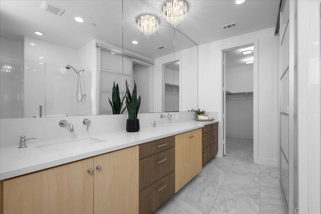 full bathroom featuring tiled shower, an inviting chandelier, marble finish floor, a sink, and visible vents