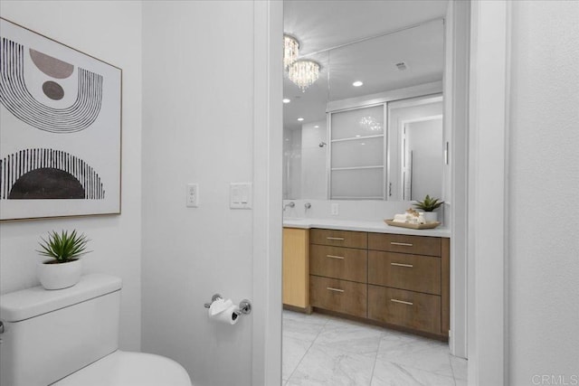 bathroom with a chandelier, toilet, recessed lighting, vanity, and marble finish floor