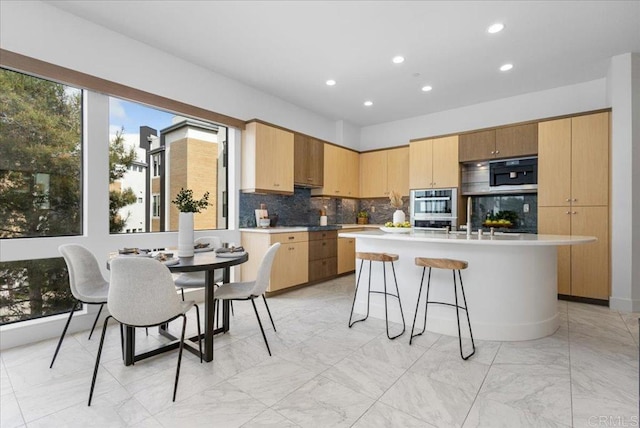 kitchen with recessed lighting, stainless steel double oven, tasteful backsplash, a breakfast bar area, and marble finish floor