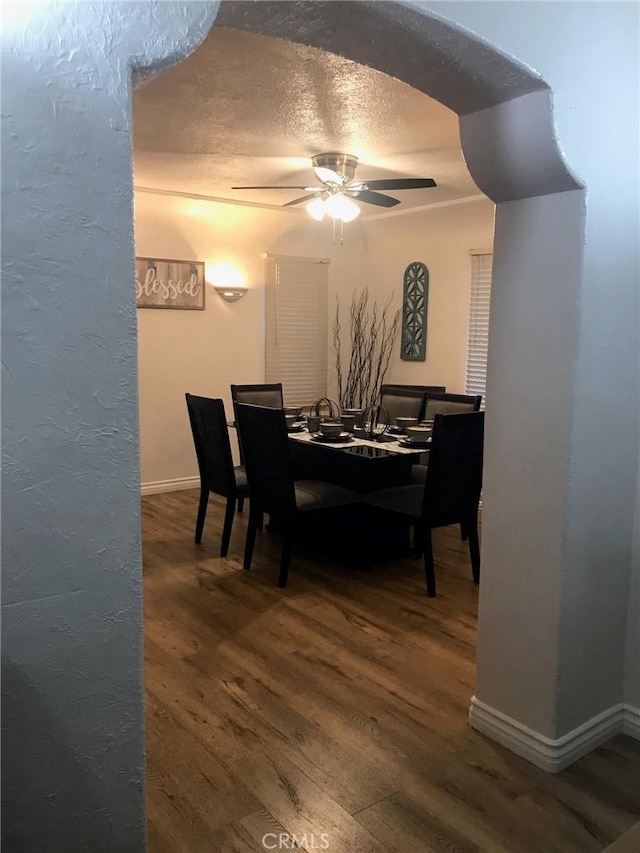 dining room with baseboards, a textured ceiling, a ceiling fan, and wood finished floors