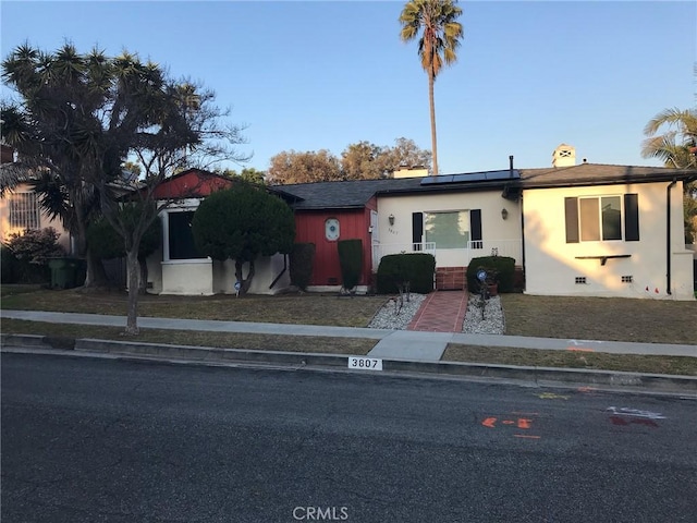 view of front facade with solar panels and stucco siding