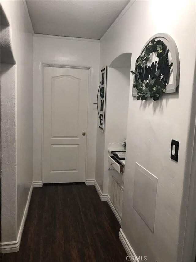 corridor featuring dark wood finished floors and baseboards