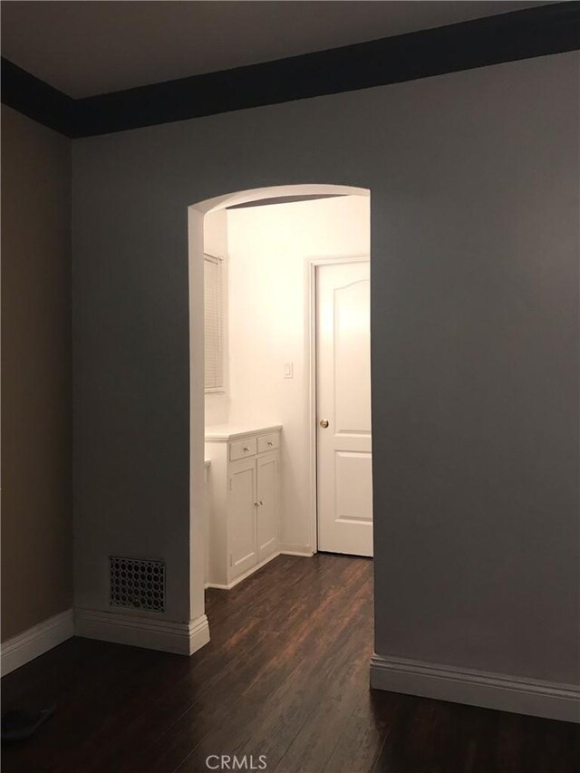 unfurnished room featuring dark wood-style floors, baseboards, and visible vents