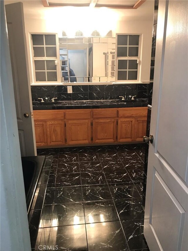 full bathroom with marble finish floor, vanity, and decorative backsplash