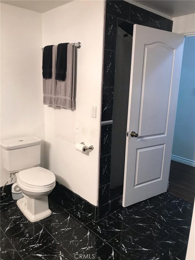 bathroom with toilet and marble finish floor