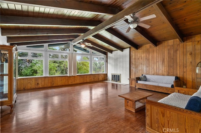 living room with a large fireplace, ceiling fan, wood-type flooring, and wooden walls