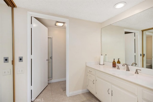 bathroom featuring vanity, baseboards, tile patterned flooring, a textured ceiling, and toilet