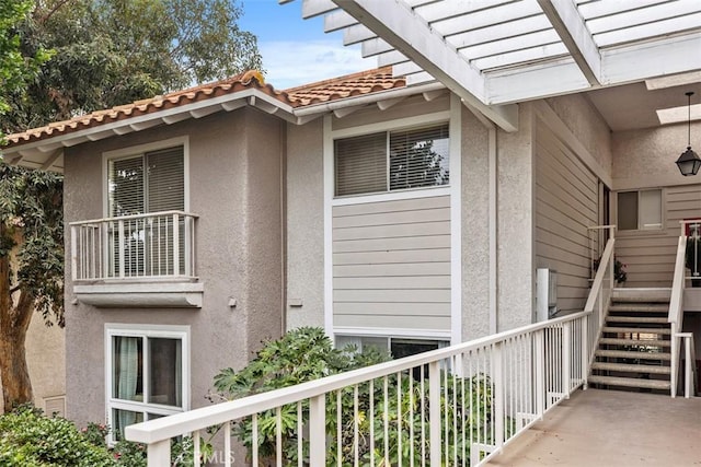 view of home's exterior with stucco siding, stairs, and a tile roof