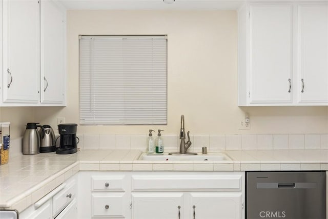 kitchen featuring stainless steel dishwasher, white cabinets, and a sink