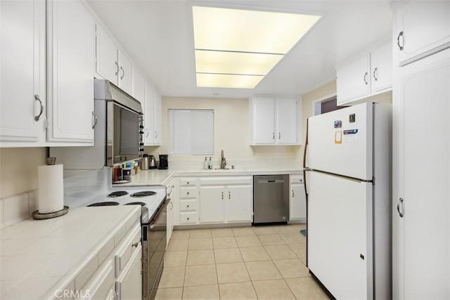 kitchen featuring white cabinetry, tile countertops, appliances with stainless steel finishes, and a sink