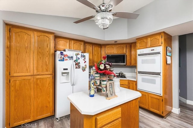 kitchen featuring white appliances, a kitchen island, light countertops, light wood-type flooring, and brown cabinets