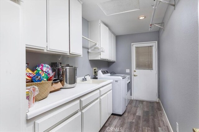 washroom featuring cabinet space, baseboards, dark wood-style floors, washing machine and clothes dryer, and a sink