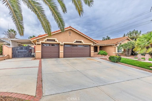 view of front of property featuring an attached garage, a tile roof, concrete driveway, a gate, and stucco siding