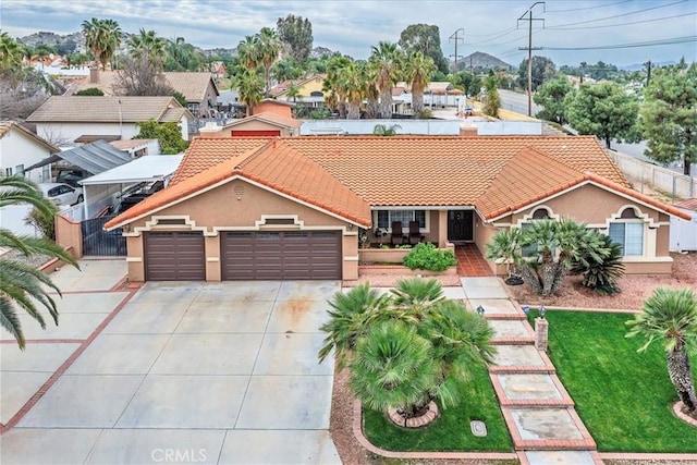 mediterranean / spanish-style house featuring driveway, a tiled roof, an attached garage, fence, and stucco siding