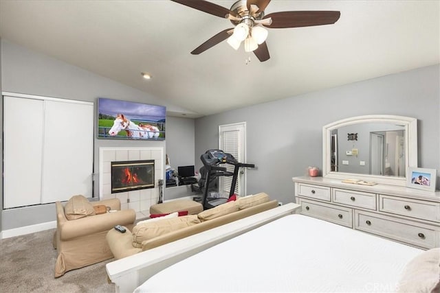 carpeted bedroom with lofted ceiling, ceiling fan, and a tile fireplace