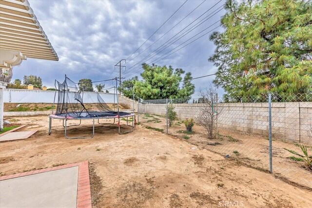 view of yard with a trampoline and a fenced backyard