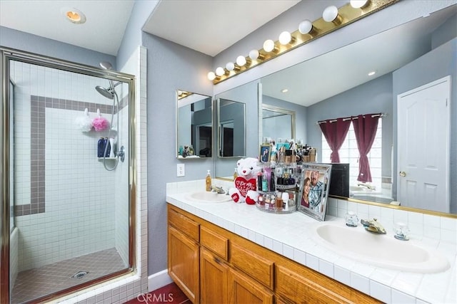 full bath featuring double vanity, a stall shower, a sink, and lofted ceiling