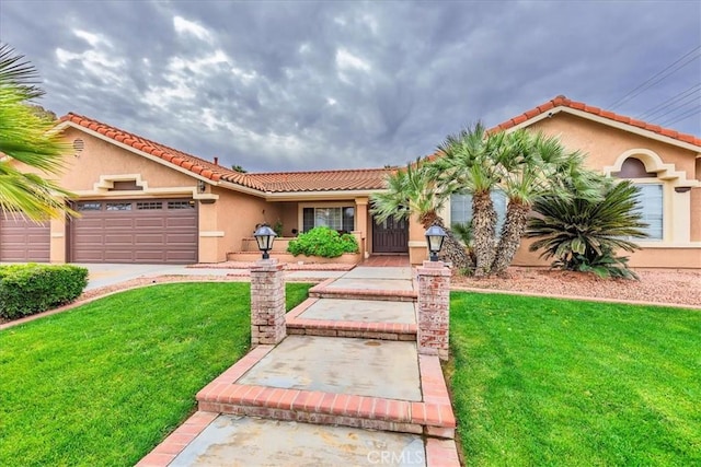 mediterranean / spanish home with a garage, a front yard, a tiled roof, and stucco siding