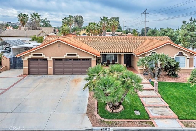 view of front of property with a garage, driveway, a tiled roof, a front lawn, and stucco siding