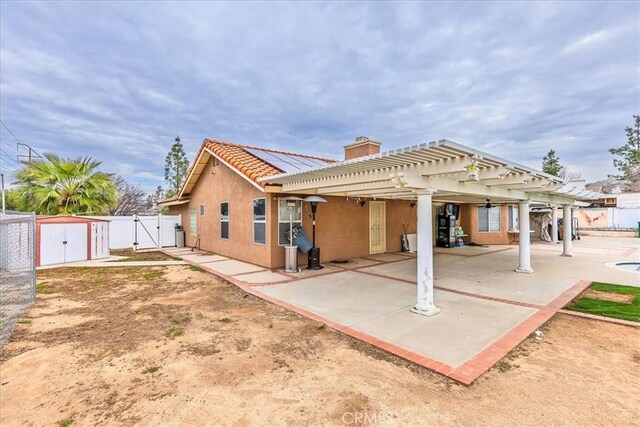 rear view of house with a tile roof, a patio, stucco siding, a gate, and fence