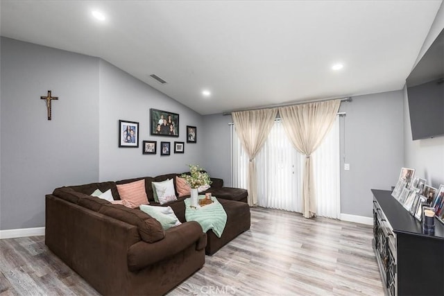 living area with lofted ceiling, light wood finished floors, baseboards, and visible vents