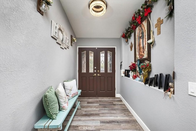 entryway featuring a textured wall, baseboards, and wood finished floors