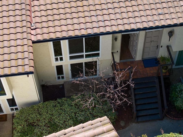 exterior details featuring a tile roof and stucco siding