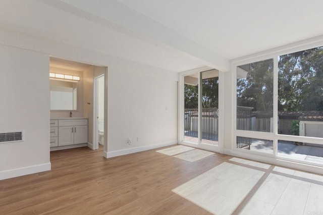 interior space with a wall of windows, wood finished floors, visible vents, and baseboards