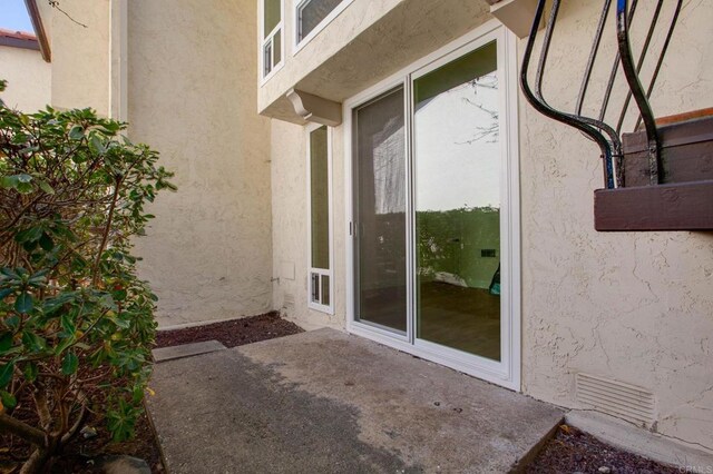 view of exterior entry featuring a patio and stucco siding