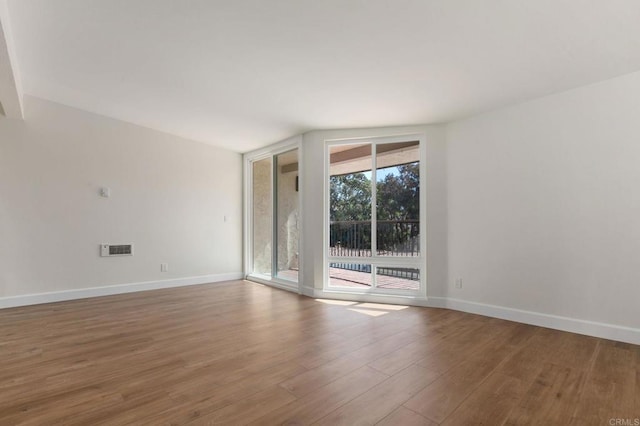 spare room with baseboards, visible vents, floor to ceiling windows, and wood finished floors