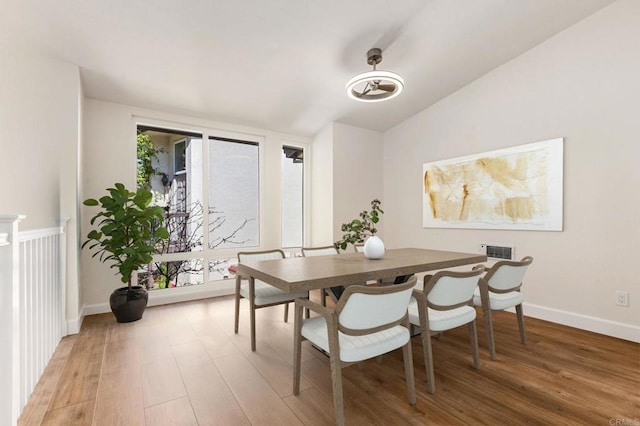 dining area featuring baseboards, light wood-style flooring, and lofted ceiling