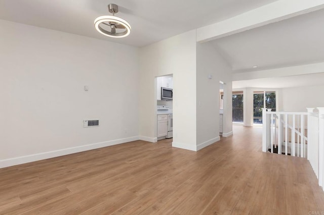 unfurnished room featuring baseboards, visible vents, vaulted ceiling, and light wood-style floors