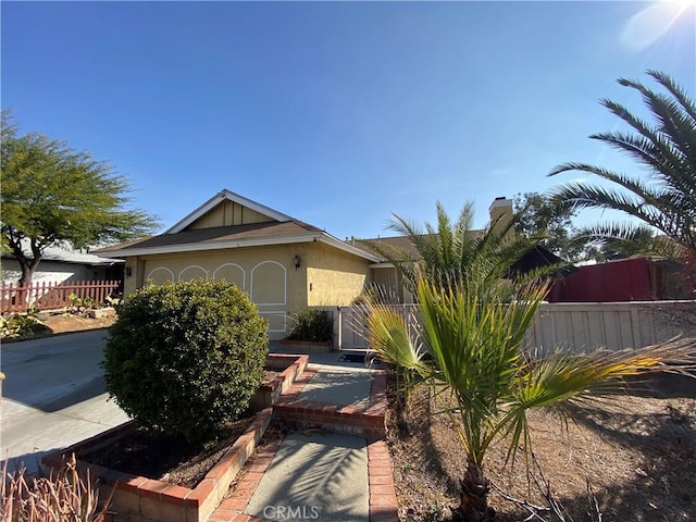 view of front of house featuring a garage, fence, driveway, and stucco siding