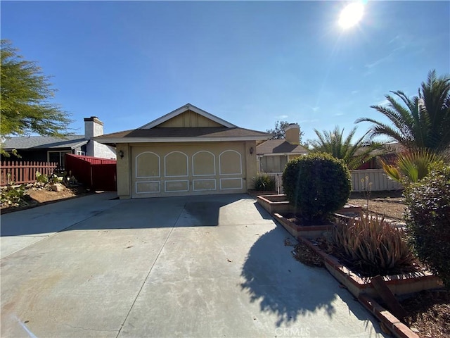 view of front of property featuring driveway, a garage, and fence