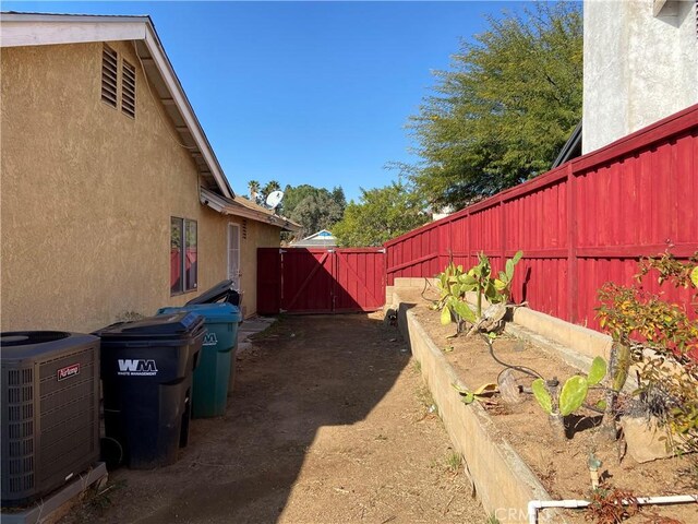 view of yard featuring a gate, fence, and central AC