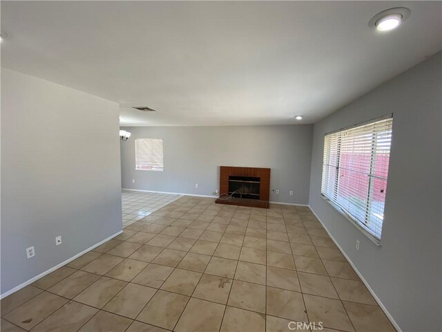 unfurnished living room with light tile patterned floors, baseboards, a fireplace, and visible vents