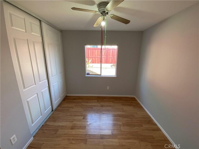 unfurnished bedroom with a closet, light wood-type flooring, a ceiling fan, and baseboards