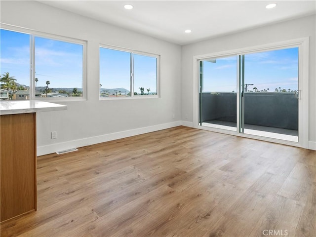 empty room with recessed lighting, light wood-type flooring, baseboards, and visible vents