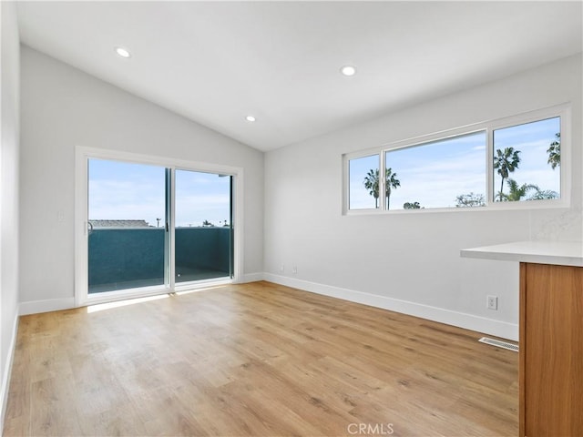 empty room featuring visible vents, baseboards, lofted ceiling, recessed lighting, and light wood-style floors