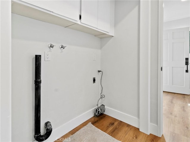 laundry room featuring light wood finished floors, cabinet space, electric dryer hookup, and baseboards