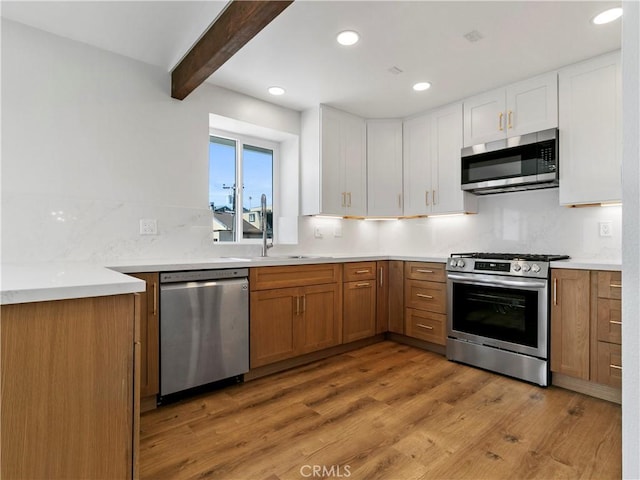 kitchen featuring beam ceiling, backsplash, white cabinetry, stainless steel appliances, and light wood finished floors